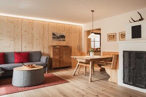A cozy living room with a sofa, round coffee table, wooden dining table, and a fireplace. - Landhaus Anna Allgäu, Bavaria (Rettenberg)