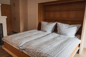 A double bed with a patterned bedspread, a wooden headboard, and a wooden wardrobe. - Landhaus Anna Allgäu, Bavaria (Rettenberg)