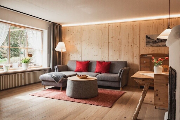 A living room with a sofa, round coffee table, and a wooden wall. - Landhaus Anna Allgäu, Bavaria (Rettenberg)