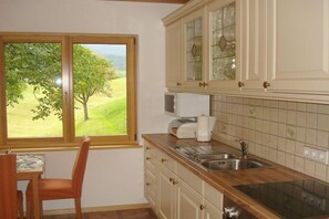 Eine Küche mit Fenster, Holzschränken, einer Spüle und einem Stuhl.