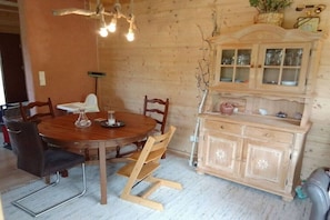 A wooden dining table with chairs, a cabinet with glass doors, and a hanging light fixture. - Holiday apartment with 1 bedroom (Pfronten)