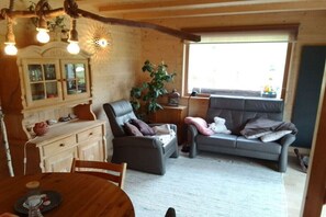 A cozy living room with a sofa, a dining table, and a wooden cabinet. - Holiday apartment with 1 bedroom (Pfronten)