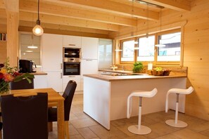 Eine moderne Küche mit weißen Schränken, einer zentralen Kochinsel, Barhocker und einem Fenster für natürliches Licht.