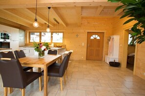Ein Holzinterieur mit einem Esstisch, Stühlen und hängenden Leuchten.