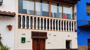 A building with a wooden door, a balcony with white balustrades, and potted plants at the entrance. - El Refugio De Los Pomares (la romana)