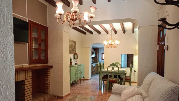 A living room with a fireplace, a dining table with chairs, and a sofa. - El Refugio De Los Pomares (la romana)