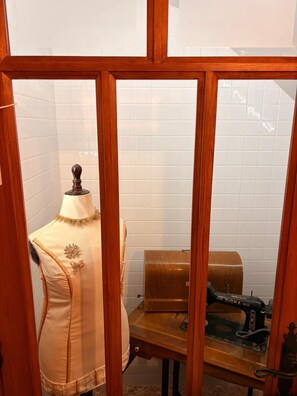 Una habitació amb un maniquí amb un vestit, una màquina de cosir i un armari de fusta.