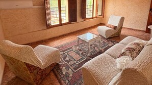 A cozy room with wooden ceiling, two windows, a patterned rug, and a sofa. - El Refugio De Los Pomares (la romana)