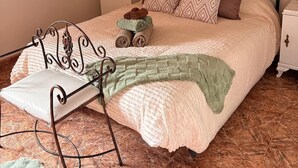 A bedroom with a metal bed frame, a bedside table, a chair, a blanket, and a painting on the wall. - El Refugio De Los Pomares (la romana)
