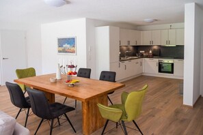 Eine moderne Küche mit weißen Schränken, einem Holzespeisetisch und schwarzen sowie grünen Stühlen.