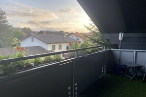 Ein Balkon mit Blick auf Häuser, einem Tisch und einem Stuhl.