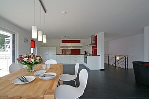 Eine moderne Küche mit weißen Schränken, einem Holzespeisetisch und einer Blumenvase.