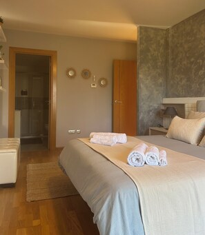 A bedroom with a bed, a bedside table, a lamp, a wardrobe, and a shower area.
