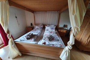 A double bed with a canopy, two bedside tables, a wall clock, and a window with curtains. - Holiday apartment in Oberstdorf with Wi-Fi (Oberstdorf)