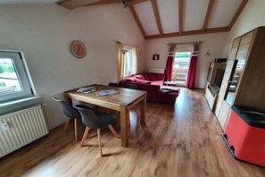 A room with a wooden dining table, chairs, a red sofa, a window, and a radiator. - Holiday apartment in Oberstdorf with Wi-Fi (Oberstdorf)