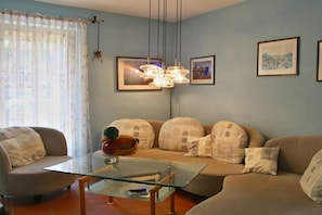 Ein Wohnzimmer mit einer Couch, einem Glastisch und einer Hängelampe.