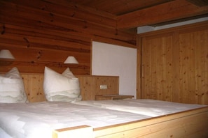 Ein Holzhütten-Zimmer mit einem Bett, zwei Nachttischlampen und einem hölzernen Kopfteil.