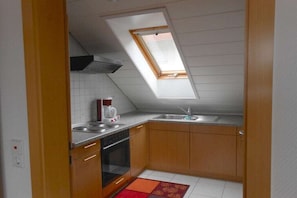 A small kitchen with a skylight, a stove, a sink, and wooden cabinets. - Holiday apartment with 2 bedrooms (Zimmern ob Rottweil, OT Horgen)