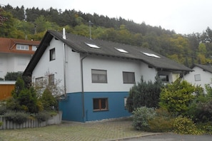 A two-story house with a sloped roof, multiple windows, and a garden area with various plants. - Holiday apartment with 2 bedrooms (Zimmern ob Rottweil, OT Horgen)