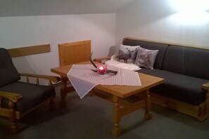 Ein Zimmer mit einem Holztisch, einem Stuhl, einem Sofa und einer Lampe.