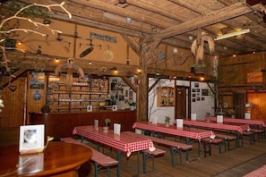 Ein rustikales Restaurant mit Holztischen, -bänken und einer Bar.