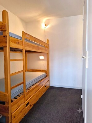 Ein Stockbett in einem Zimmer mit weißen Wänden und Teppichboden.