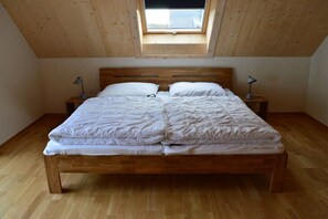 Ein Schlafzimmer mit einem hölzernen Bett, zwei Nachttischen, einem Oberlicht und einem Holzboden.