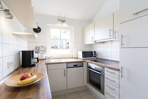 Eine moderne Küche mit weißen Schränken, einer Mikrowelle, einem Backofen und einem Geschirrspüler.