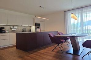 Eine moderne Küche mit Kochinsel, integrierten Geräten und einem Essbereich mit Tisch und Stühlen.