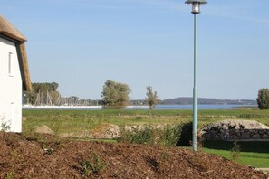 Eine ländliche Landschaft mit einem weißen Gebäude, einer Steinmauer und einem Metalllichtpfahl.