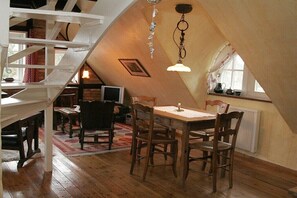 Ein Loft-Zimmer mit Esstisch, Stühlen, einer Wendeltreppe und einem Fenster mit Blick.