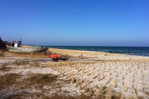 A beach with a row of boats, a lifeguard tower, and a sandy area with sparse vegetation. - Holiday apartment in Zingst with Wi-Fi (Zingst)