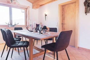 A dining area with a wooden table, black chairs, a candle holder, and a decorative wall piece. - Holiday apartment with 1 bedroom (Telfes im Stubaital)