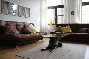 A living room with two brown leather sofas, a glass coffee table, and a decorative dog statue. - Holiday apartment with 1 bedroom (Nordwestuckermark)
