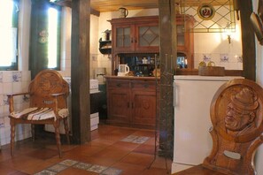 A kitchen with wooden cabinets, a coffee maker, and a refrigerator. - The green cottage - Below (Ostseebad Prerow)