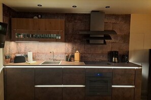 Eine moderne Küche mit dunklen Schränken, einer Edelstahl-Spüle und einem eingebauten Backofen.