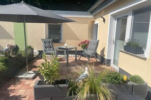 Eine Terrasse mit Tisch und Stühlen, einer Vogel-Skulptur und Pflanzgefäßen.