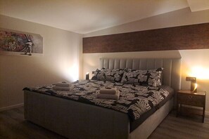 Ein Schlafzimmer mit einem Bett, einem Nachttisch, einem Wandbild und einer Deckenplatte.