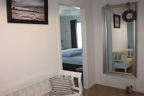 Ein Zimmer mit einem Bett, einem Sessel, einem Spiegel und einem gerahmten Bild an der Wand.
