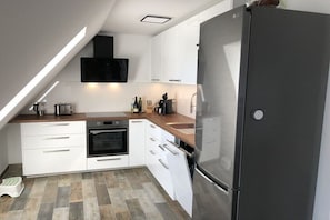 Eine moderne Küche mit weißen Schränken, einem Edelstahlkühlschrank und einem eingebauten Backofen.