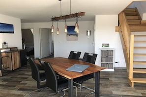 Ein moderner Essbereich mit Holztisch, schwarzen Stühlen und einer Pendelleuchte.