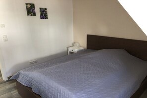 Ein Schlafzimmer mit einem Bett, einem Nachttisch und zwei Bildern an der Wand.