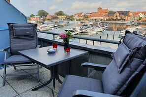 Ein Balkon mit Tisch, zwei Stühlen und einem Blumenarrangement.