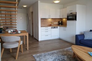 Eine moderne Küche mit weißen Schränken, einer Holz Arbeitsplatte und einem eingebauten Ofen.