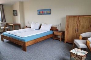 Ein Hotelzimmer mit einem hölzernen Bett, einem Schreibtisch, einem Stuhl, einem Kleiderschrank und einem Bild an der Wand.
