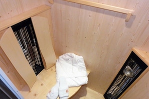 Ein Holzraum mit einer Bank, einem kleinen Regal und einem Metallgestell.