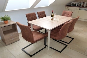 Ein Essbereich mit Tisch, Stühlen, einer Weinflasche und einem Glas.