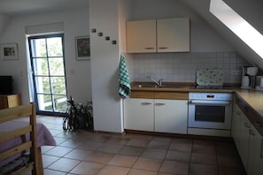 A kitchen with a window, a sink, a stove, and cabinets. - Holiday apartment with 2 bedrooms (Putbus \/ OT Güstelitz)