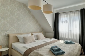 Ein modernes Hotelzimmer mit einem Bett, einem Nachttisch, einer Lampe und einem Fenster mit Vorhängen.