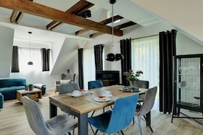 Ein modernes Wohnzimmer mit einem Holzesstisch, blauen Stühlen, einem Sofa und einem Fernseher.